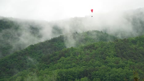 parapentes extremos que descienden lentamente sobre la montaña que se vaporiza después de la lluvia en danyang, corea del sur