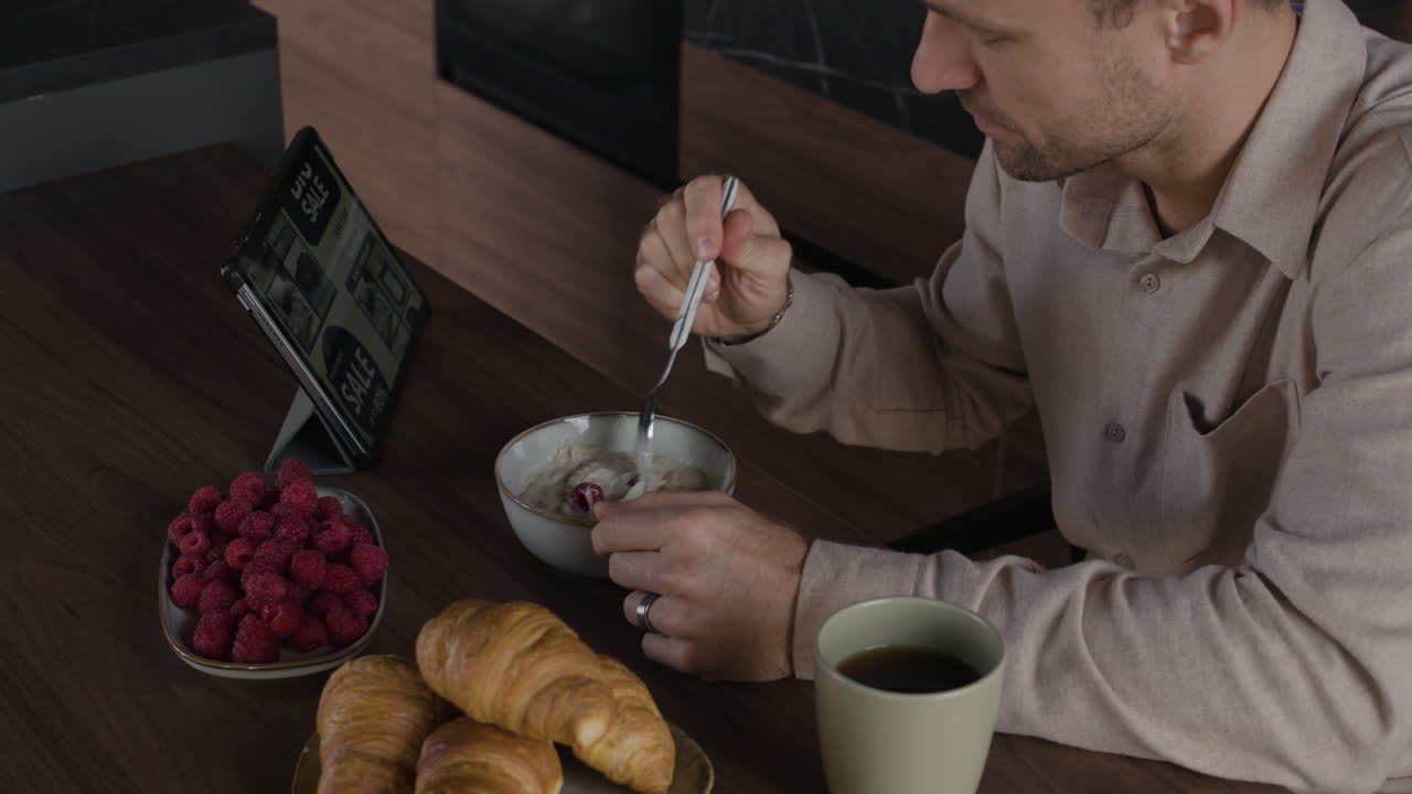 Man having breakfast while using tablet