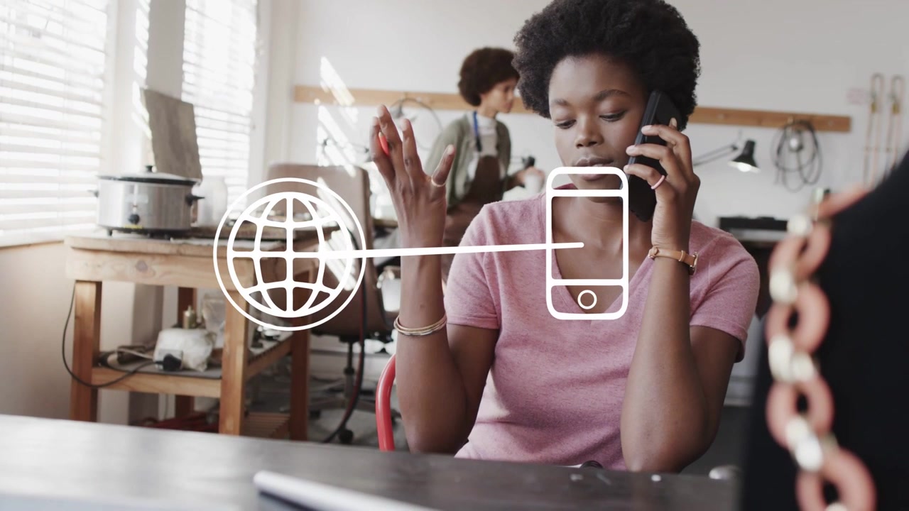 Woman on call while jotting design notes in workshop, animated globe linking smartphone for design
