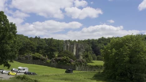 drone taking off over fields and old castle ruins on a warm sunny day with blue sky and clouds