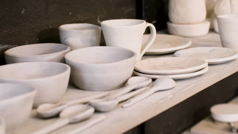 close up of various ceramic dishware on a wooden shelf in the pottery shop