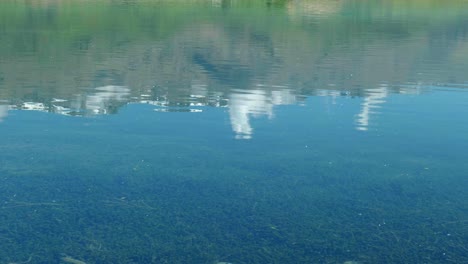 Snowy-peaks-mirror-in-tranquil-water-ripples,-creating-a-mesmerizing-alpine-reflection