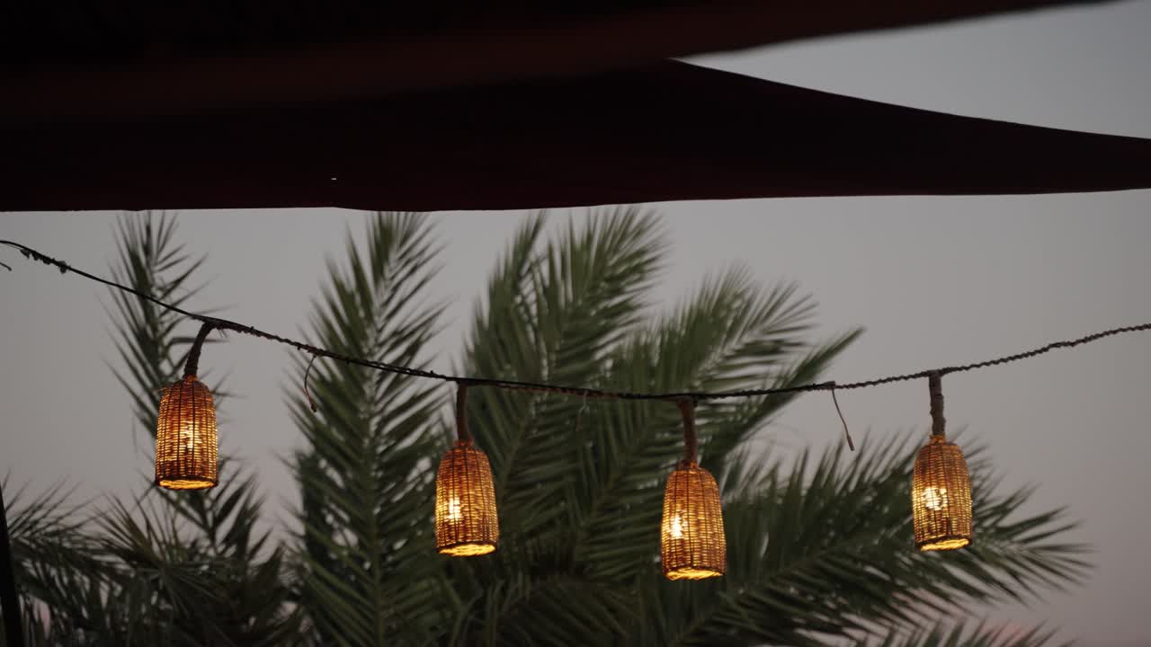 Wicker lanterns glowing at dusk with palm trees in the Medina of Marrakech