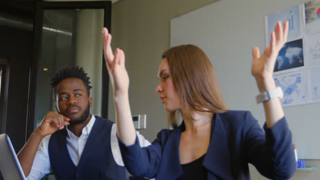 Side-view-of-young-mixed-race-business-team-planning-and-sitting-with-laptop-in-a-modern-office-4k