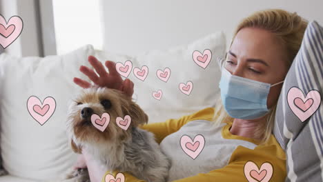 animación de corazones moviéndose sobre una mujer caucásica con máscara facial sosteniendo a su perro mascota