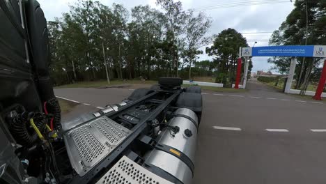 perspectiva trasera de un camión maniobrando un giro en u en una carretera rural bajo un cielo nublado con bosques a ambos lados