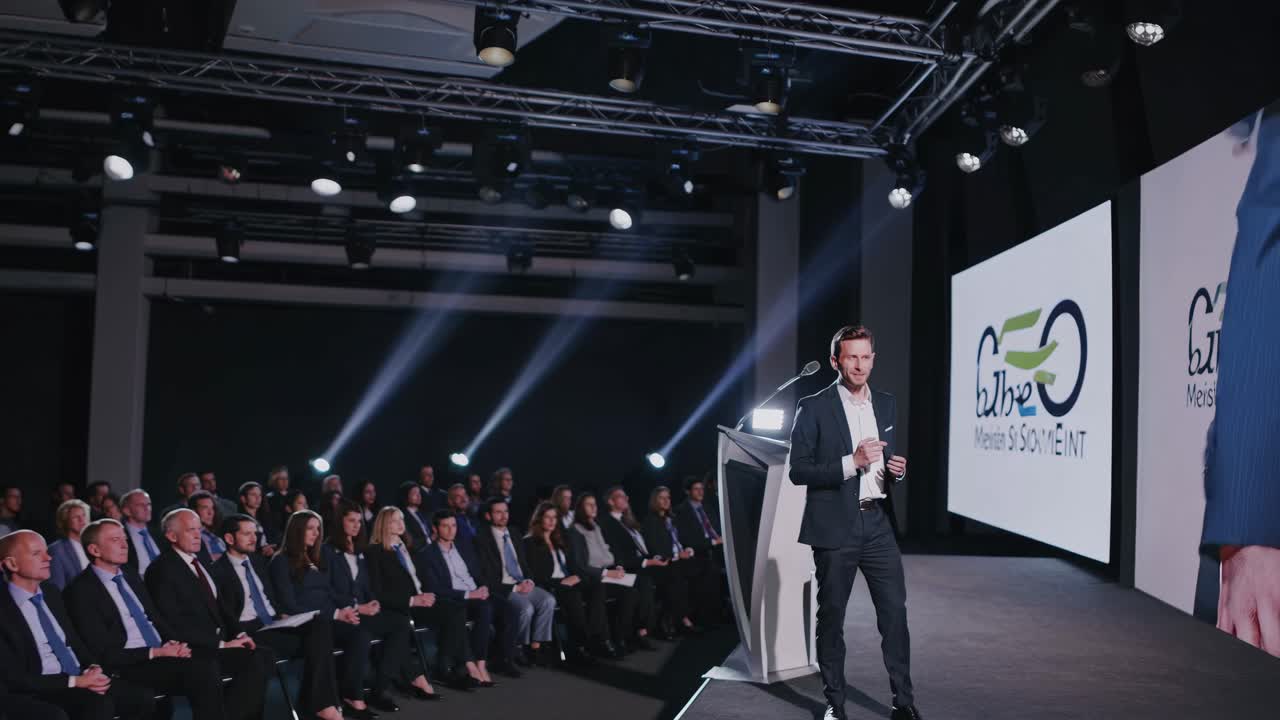 A professional video captures a speaker on stage at a business conference video