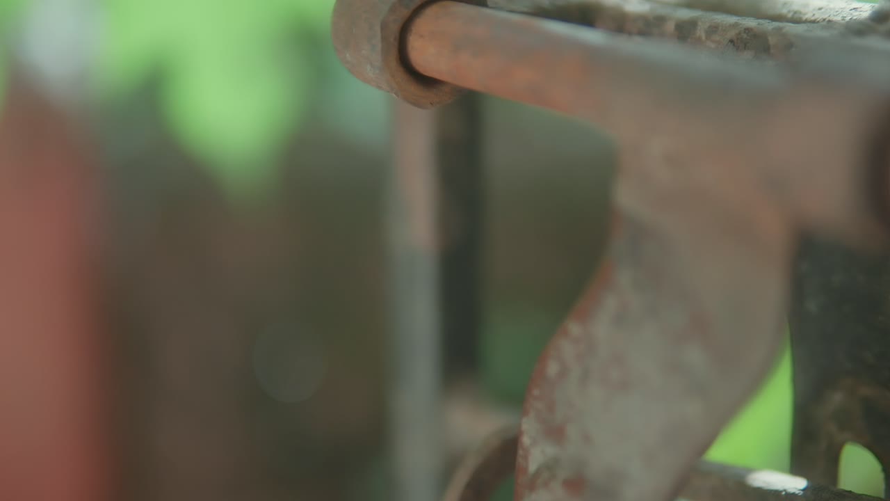 Rusty metal hinge on an old gate in close-up with green blurred background