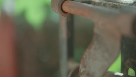 Rusty-metal-hinge-on-an-old-gate-in-close-up-with-green-blurred-background