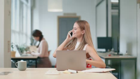 Junge-Frau,-Die-Im-Coworking-Am-Computer-Arbeitet.-Lächelnde-Dame,-Die-Mit-Dem-Handy-Chattet.