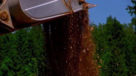 slow motion close up of excavator shovel let falling rocks and stone at construction site