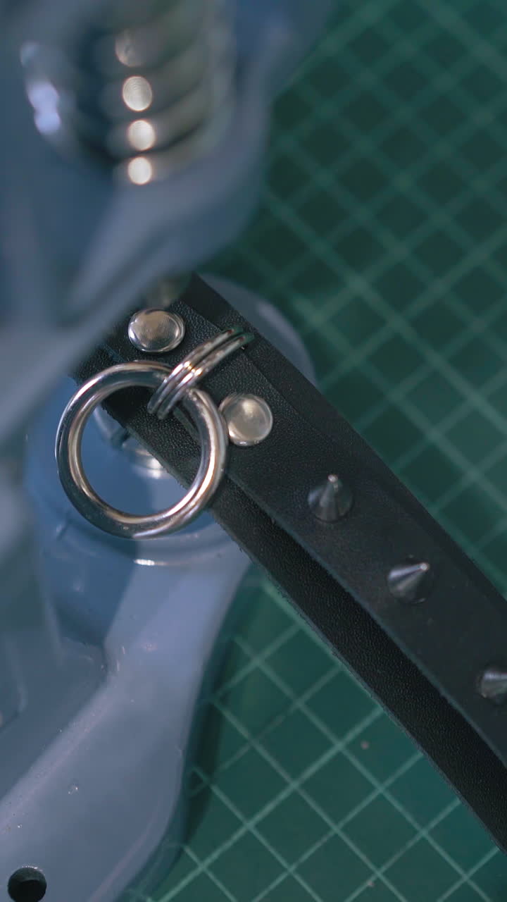 CU: Skilled designer sets metal accessories on fashionable black leather choker with press machine closeup