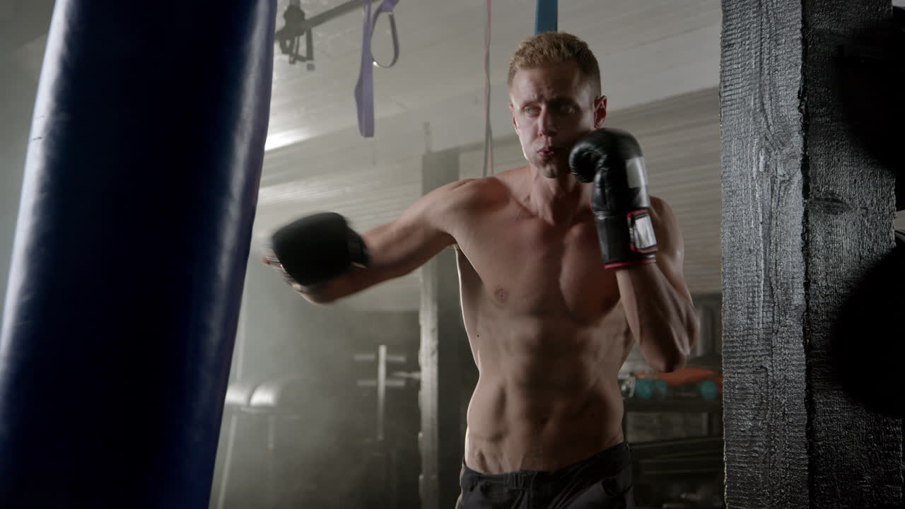 A muscular man boxing with a punching bag in a gym
