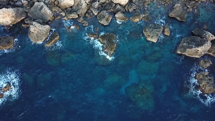 Ripresa con drone di un paesaggio roccioso a Malta, con panoramica verso il basso sull'oceano blu e limpido.