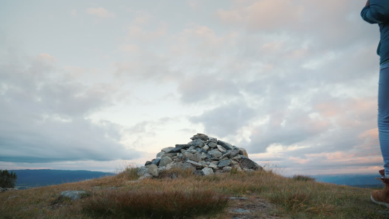 el viajero asciende a la cima de la montaña donde un pequeño montículo yace la dura naturaleza de noruega