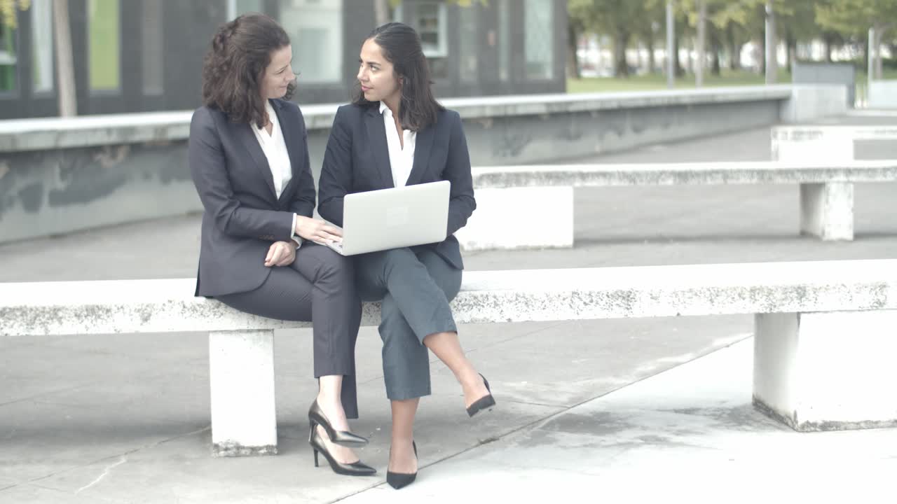 Experienced businesswomen sitting outdoors with laptop