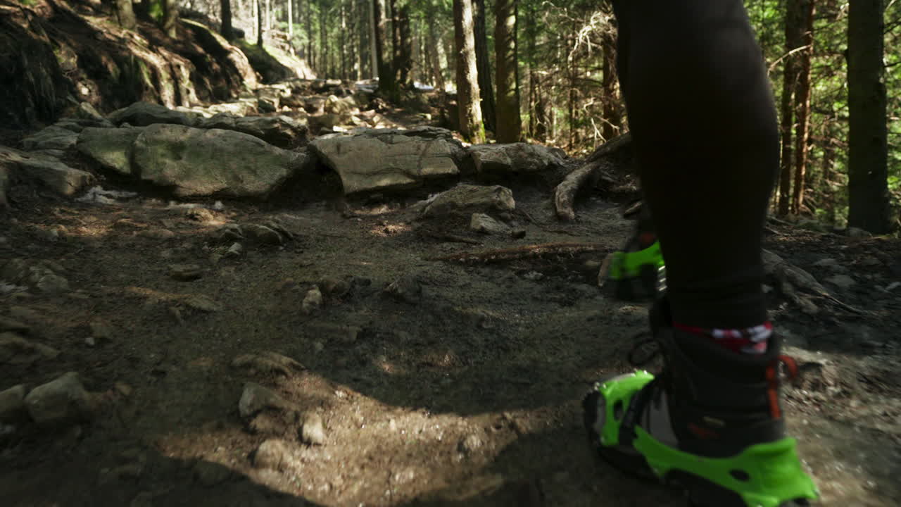 Hiker walking with crampons on a forest trail. Slow motion tracking shot