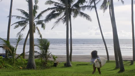 donna che attraversa il giardino con una tavola da surf