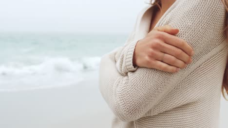 sección media de una mujer caucásica caminando con los brazos cruzados en la playa 4k