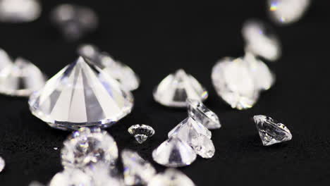 slow-motion close-up shot of real shining brilliant-cut diamonds throwing the black sorting table in a jewelry store for further selection and sale