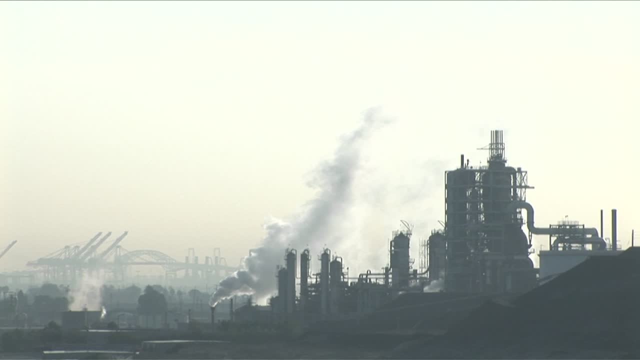 Smoke rises from a petrochemical factory or oil refinery under a cloudy sky