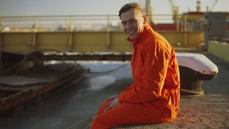 retrato de un joven trabajador en uniforme naranja sentado durante su descanso junto al mar