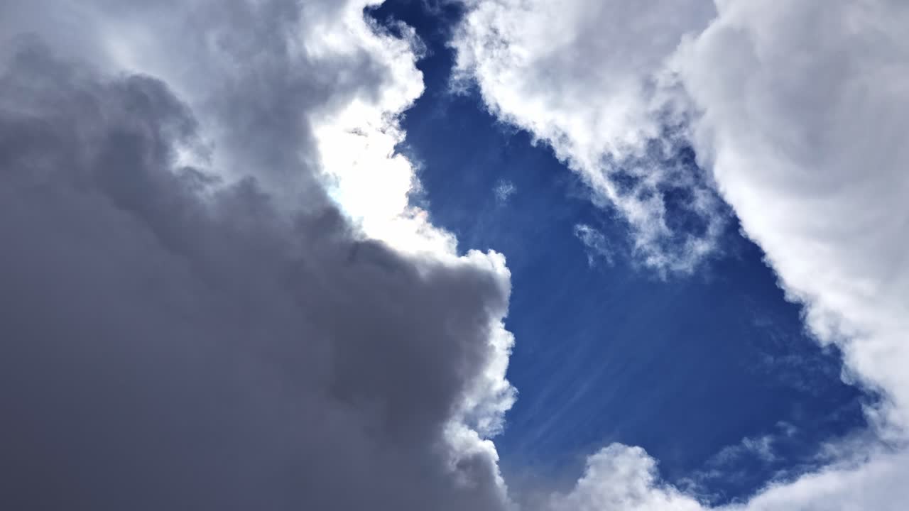 A beautiful timelapse shows the bright sun appearing and disappearing as white and grey clouds drift across a blue sky, with rays of light breaking through