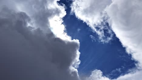 a beautiful timelapse shows the bright sun appearing and disappearing as white and grey clouds drift across a blue sky, with rays of light breaking through