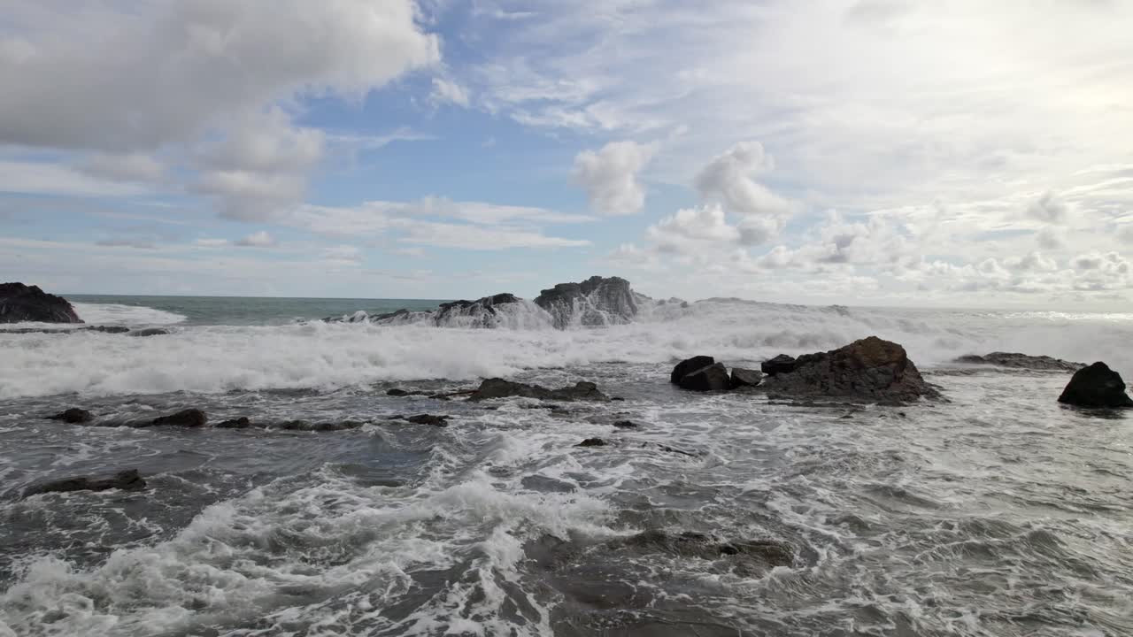 muñeca aérea volando sobre las espumosas olas del mar golpeando la escarpada costa en un día nublado en la playa dominicalito, costa rica