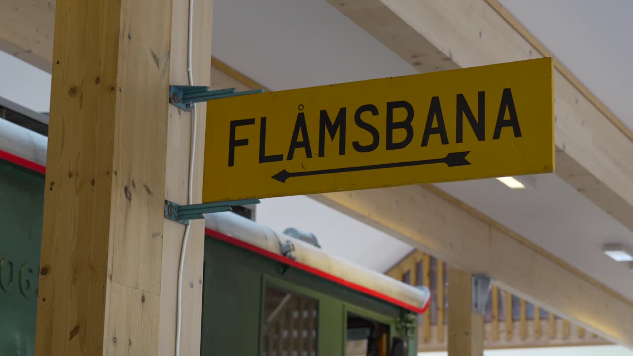 Interior shot from Flåm Railway Museum, Norway, featuring FLÅMSBANA directional signage and vintage train car in a timber-framed station setting