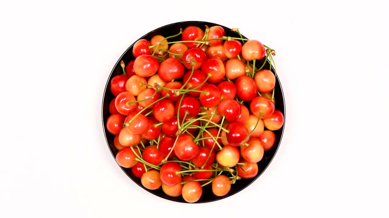 Ripe juicy yellow sweet cherries on plate. Side view. Clockwise rotation. Loop motion.