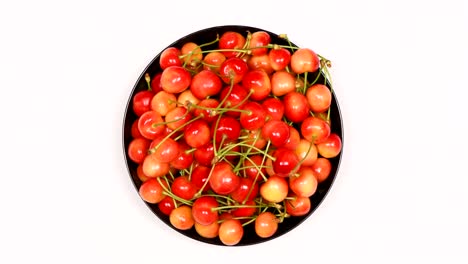 ripe juicy yellow sweet cherries on plate. side view. clockwise rotation. loop motion.
