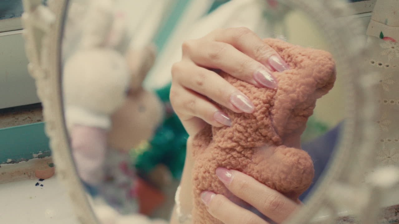 Woman Holding Teddy Bear in Front of a Mirror