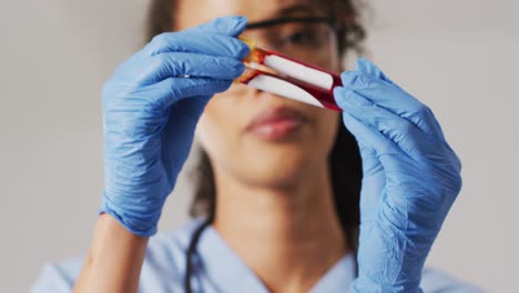 video de una doctora biracial sosteniendo un tubo de ensayo sobre un fondo azul