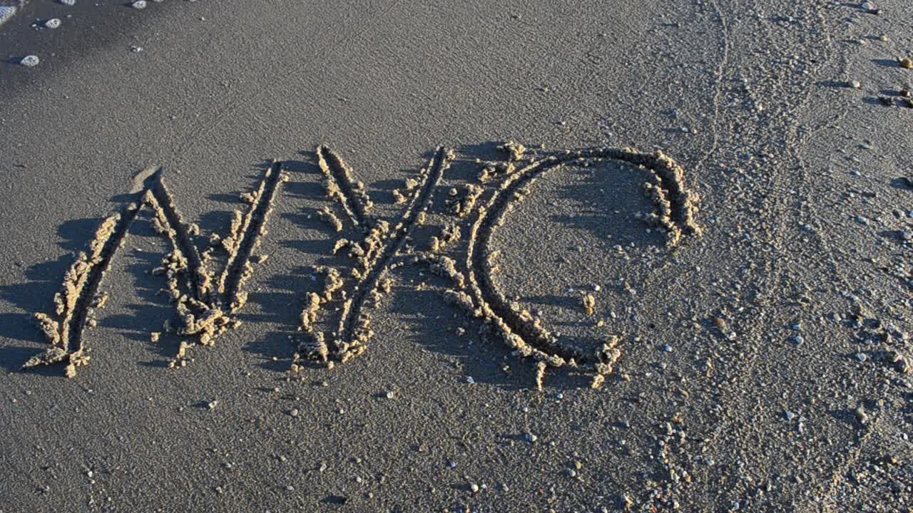 The inscription NYC on sand. Inscription on sand, the beach
