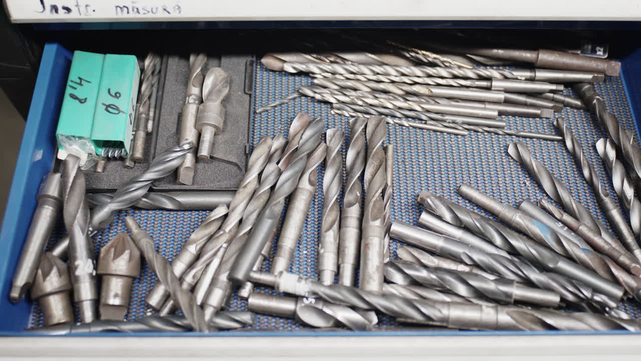 Shot over a blue workshop drawer filled with various metal drill bits