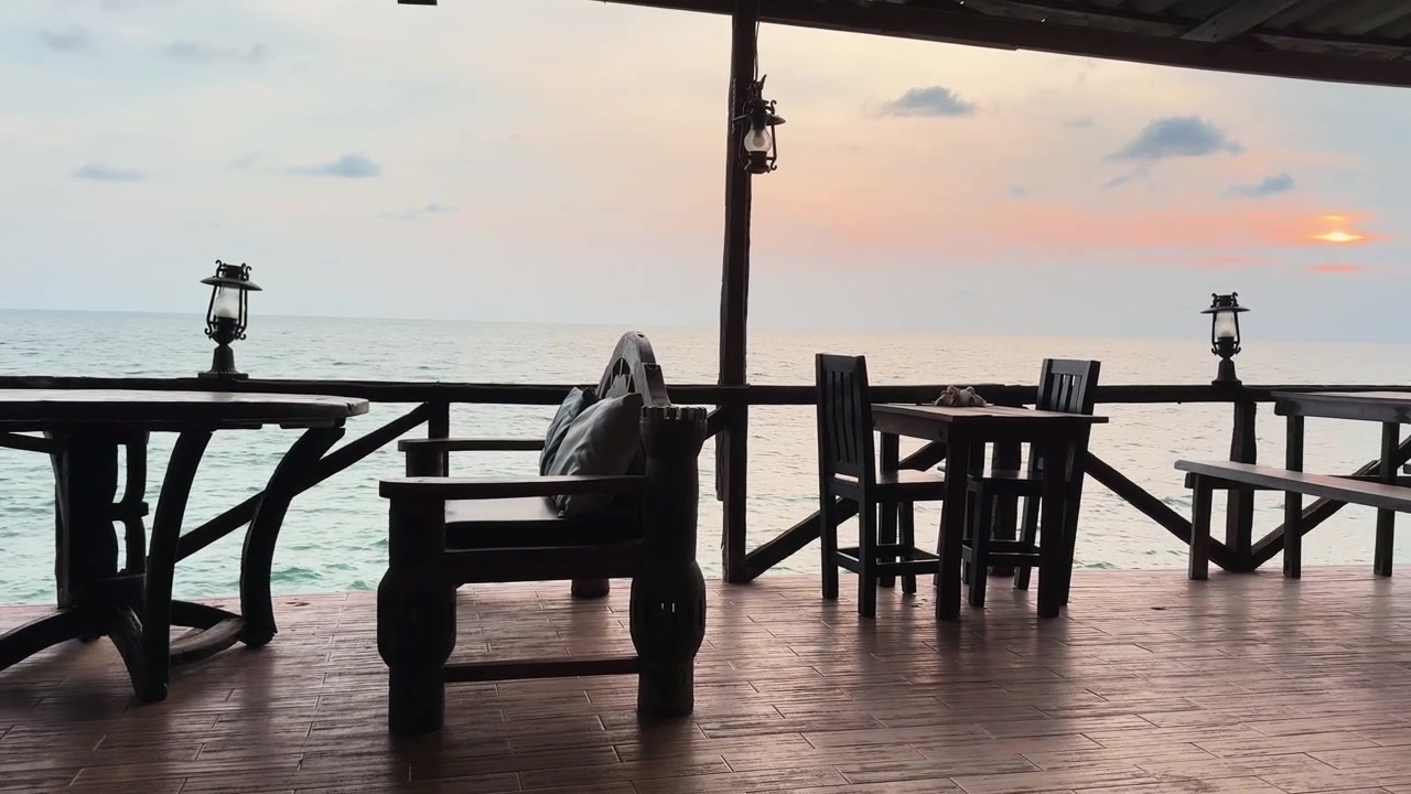 Wooden seaside pier and waterfront seating overlooking calm tropical water on Koh Chang, Thailand, creating a quiet and relaxed island resort atmosphere