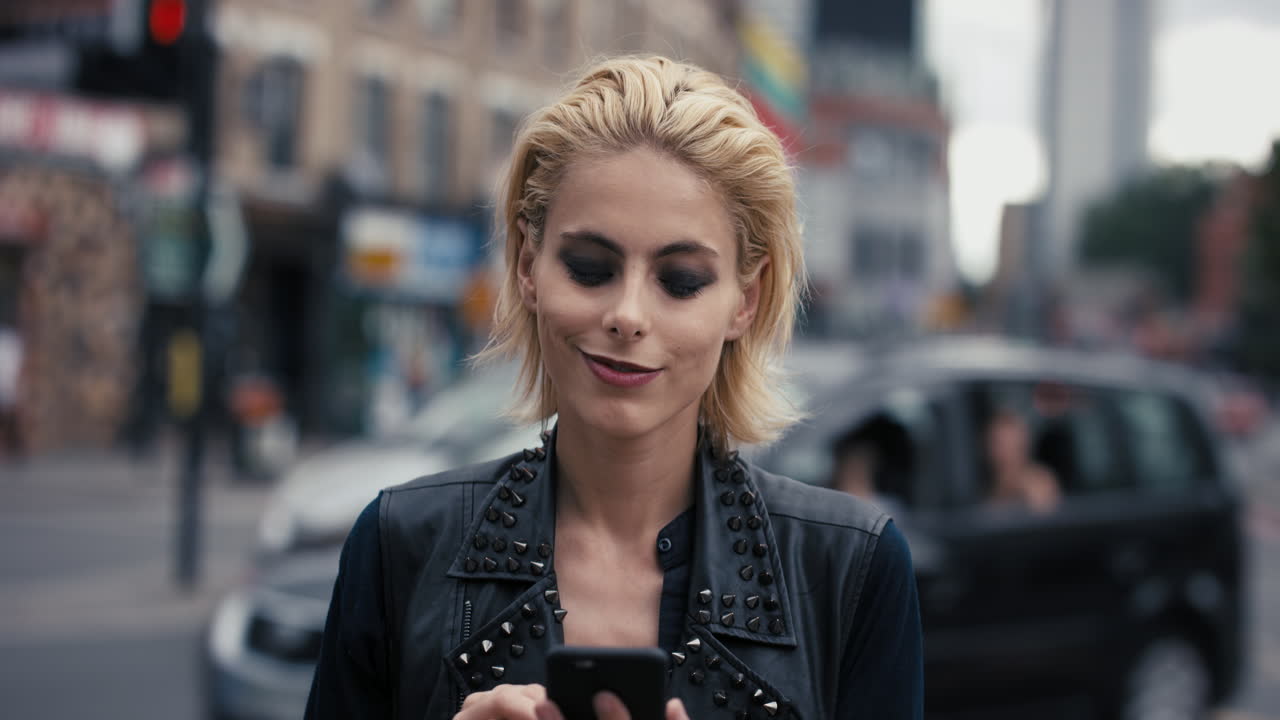 Ritratto al rallentatore di una donna punk caucasica felice e bellissima che usa lo smartphone
