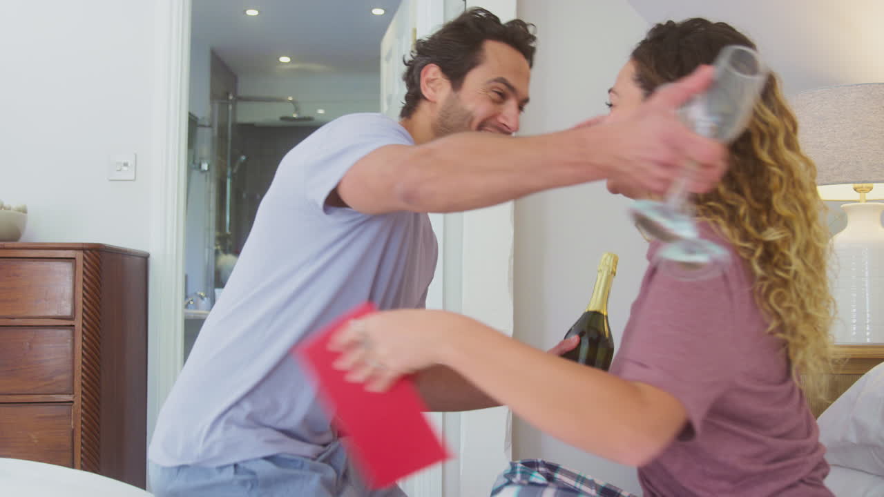 사랑하는 커플이 집에서 침대에서 피자마를 입고 카드와 꽃으로 생일이나 기념일을 축하합니다.