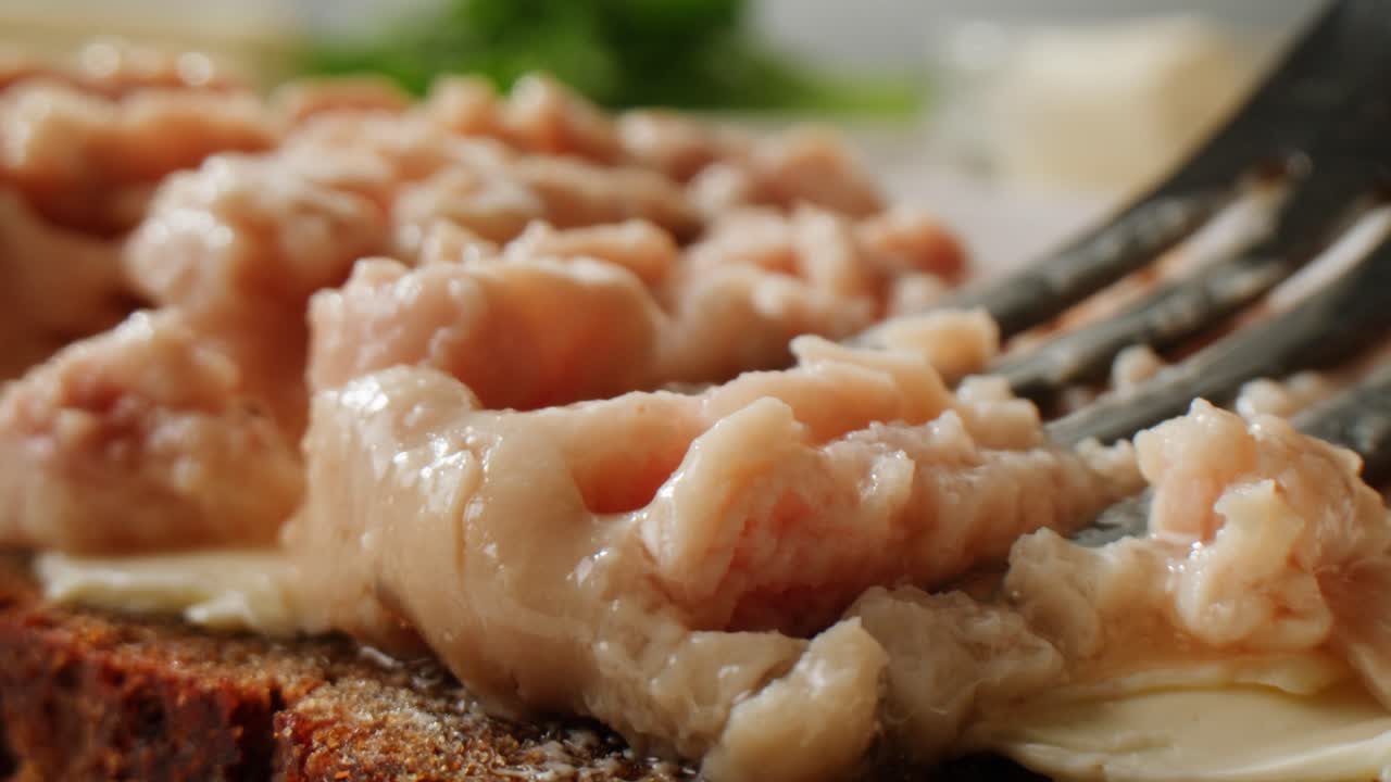 Smoked cod liver in oil in open tin can with fresh greens on wooden table. Seafoods delicacy. High quality 4k footage