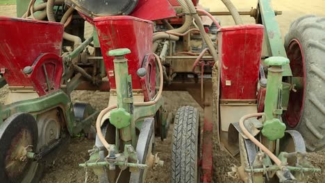 seed sowing hydraulic seed machine mounted on red tractor, close up of agricultural farming equipment for seed and land preparation