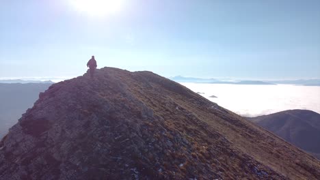 fearless female hiker hiking on the edge of a mountain drone shot