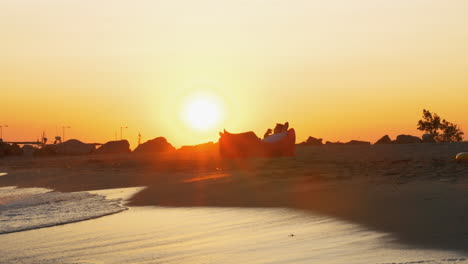 man relaxing in inflatable sunbed on the beach at sunset