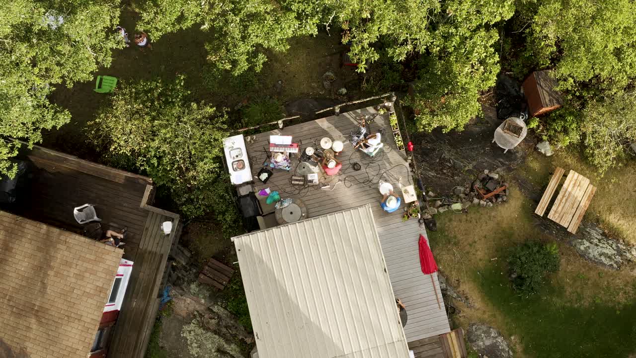 Top-down aerial descend over top of musicians playing their instruments for a dancing audience off stage.  Aerial 4k.