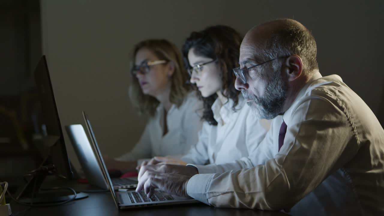 어두운 사무실에서 노트북을 가진 피곤한 사업가들