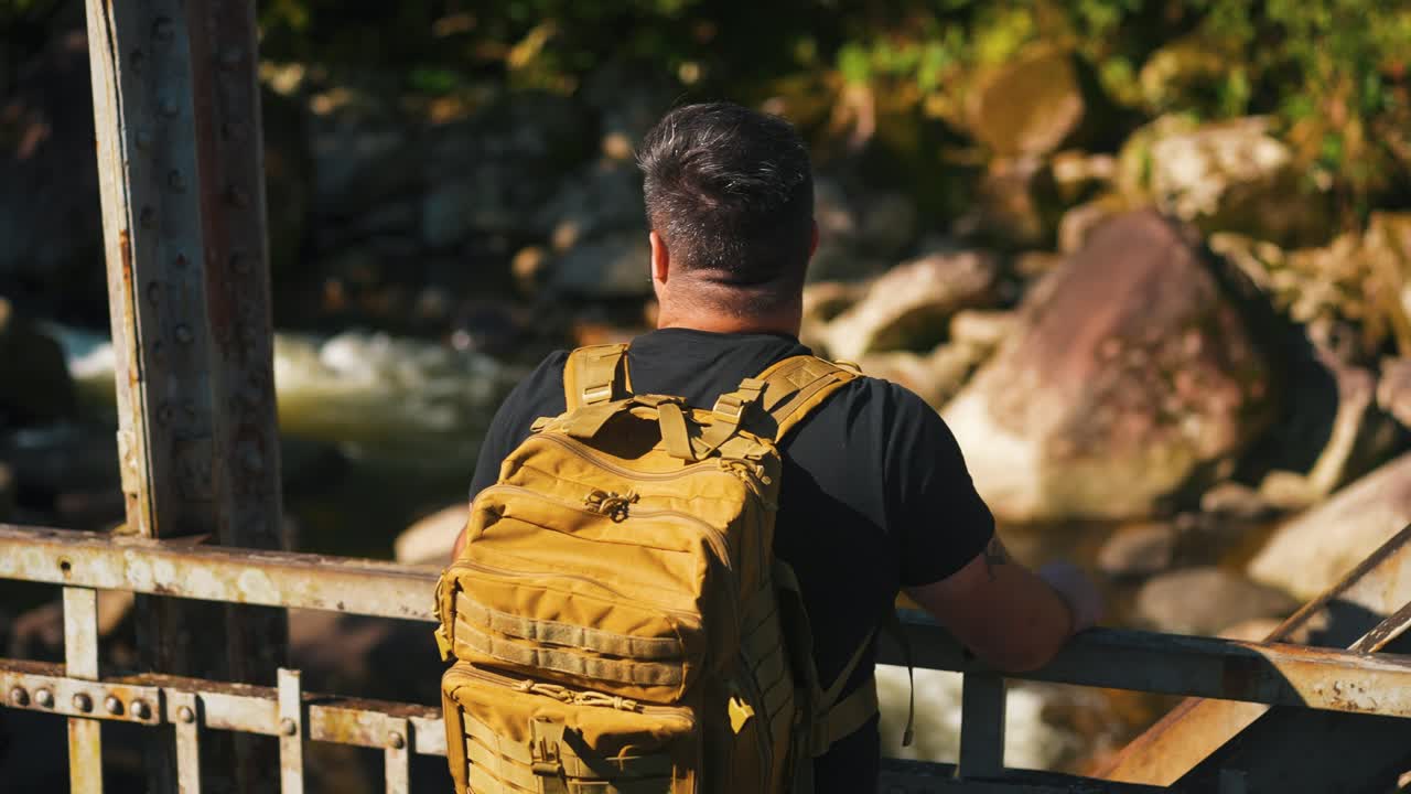 joven viajero admirando la naturaleza en el viejo puente oxidado al aire libre en un soleado día de verano