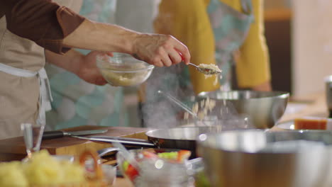 chef adding cheese to frying pan while giving cooking master class