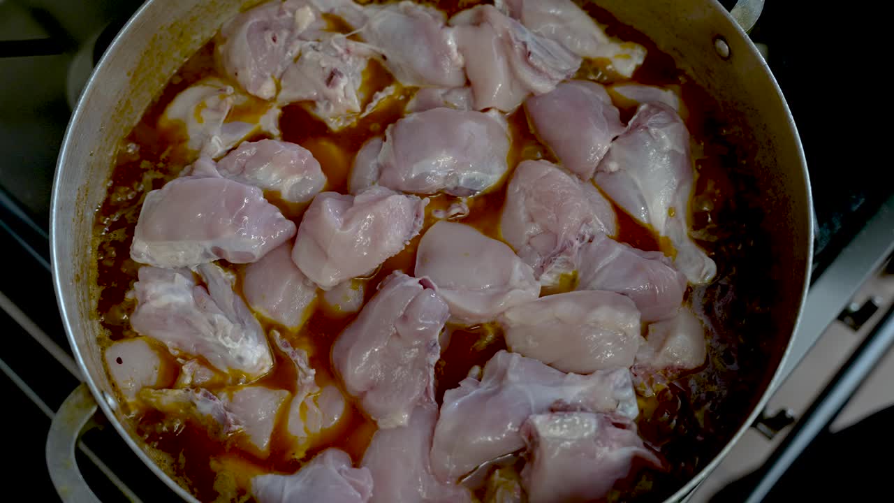 pezzi di pollame crudo vengono messi e cotti in salsa di curry bollente in pentola