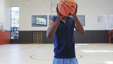 Close-up-of-african-american-male-basketball-player-shooting-ball-at-indoor-court,-slow-motion