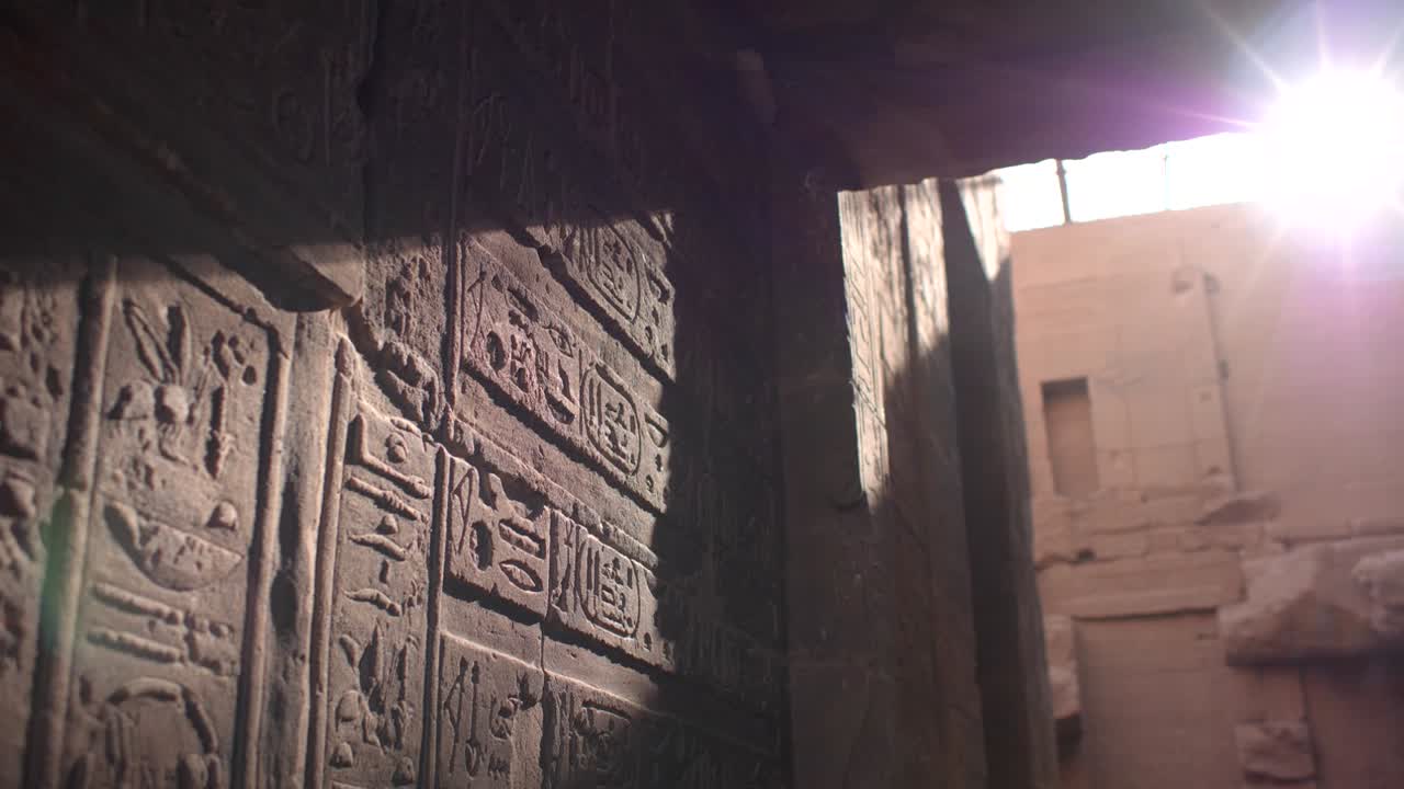 Close detail of sunrays hitting hieroglyphs on the walls inside the temple of Philae, Aswan, Egypt.